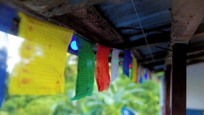A structure with a corrugated metal roof and colorful flags hanging from it. - Nama Stay Home (Pokhara)