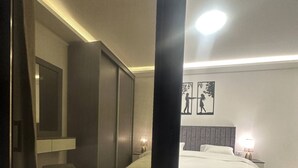 A modern bedroom with a large bed, a bedside table, a nightstand, and a wall-mounted TV.
