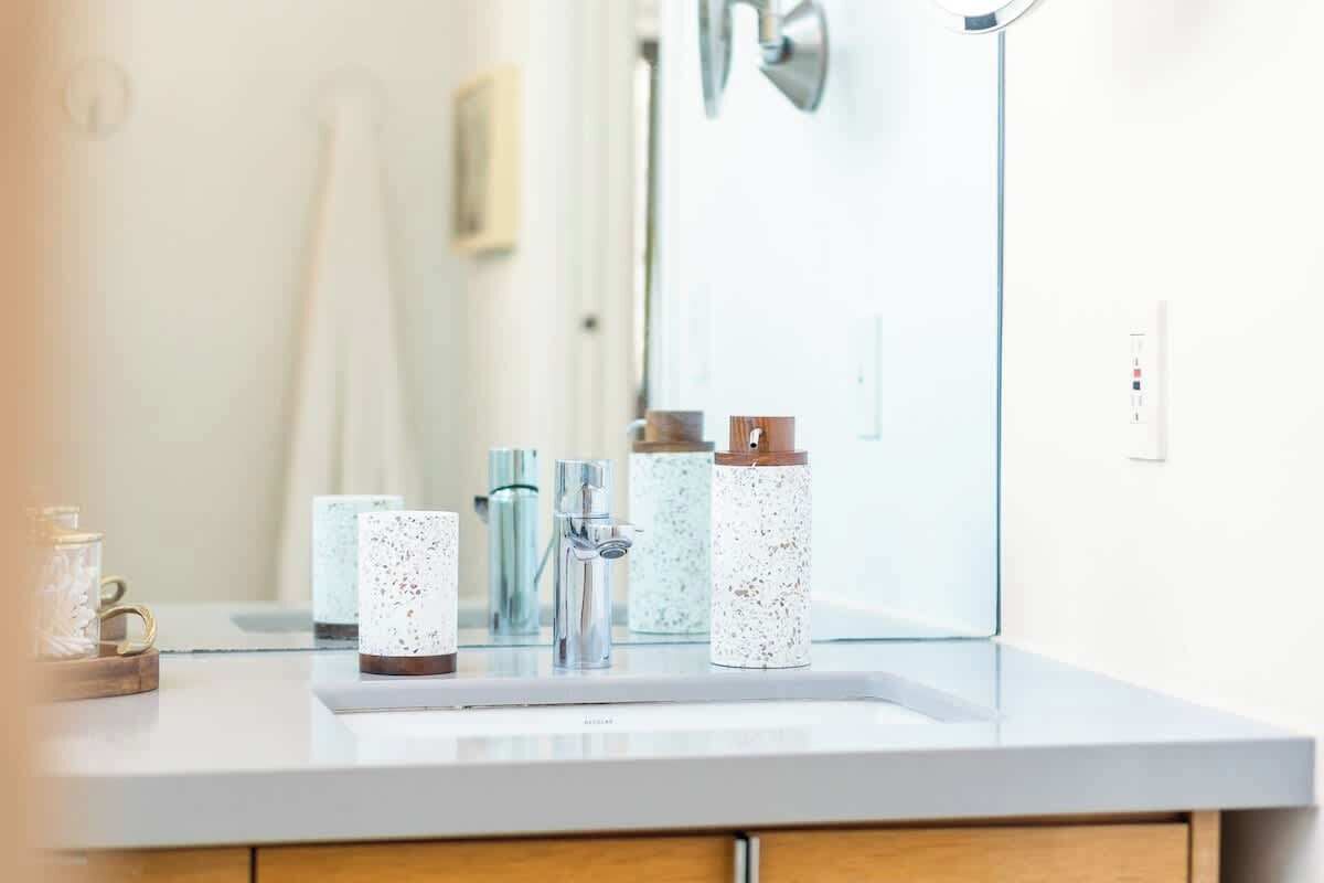 Une salle de bain avec un lavabo blanc, un miroir et trois distributeurs de savon à motifs.