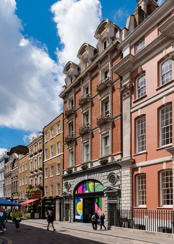 A historic building with a prominent archway entrance, classic architecture, and a paved street in front.