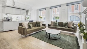 Una sala de estar moderna con un conjunto de sofás, una mesa de centro y una cocina al fondo.