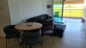 A modern living room with a round wooden table, black chairs, and a black sofa with cushions. - Spacious 2-bed Apartment in Sotira With Pool (Sotira)