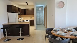 A modern kitchen with dark cabinets, a white refrigerator, and a central island with bar stools. - Spacious 2-bed Apartment in Sotira With Pool (Sotira)