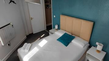 Una camera d'albergo con un letto, comodini, un termosifone e una porta che dà accesso al bagno.