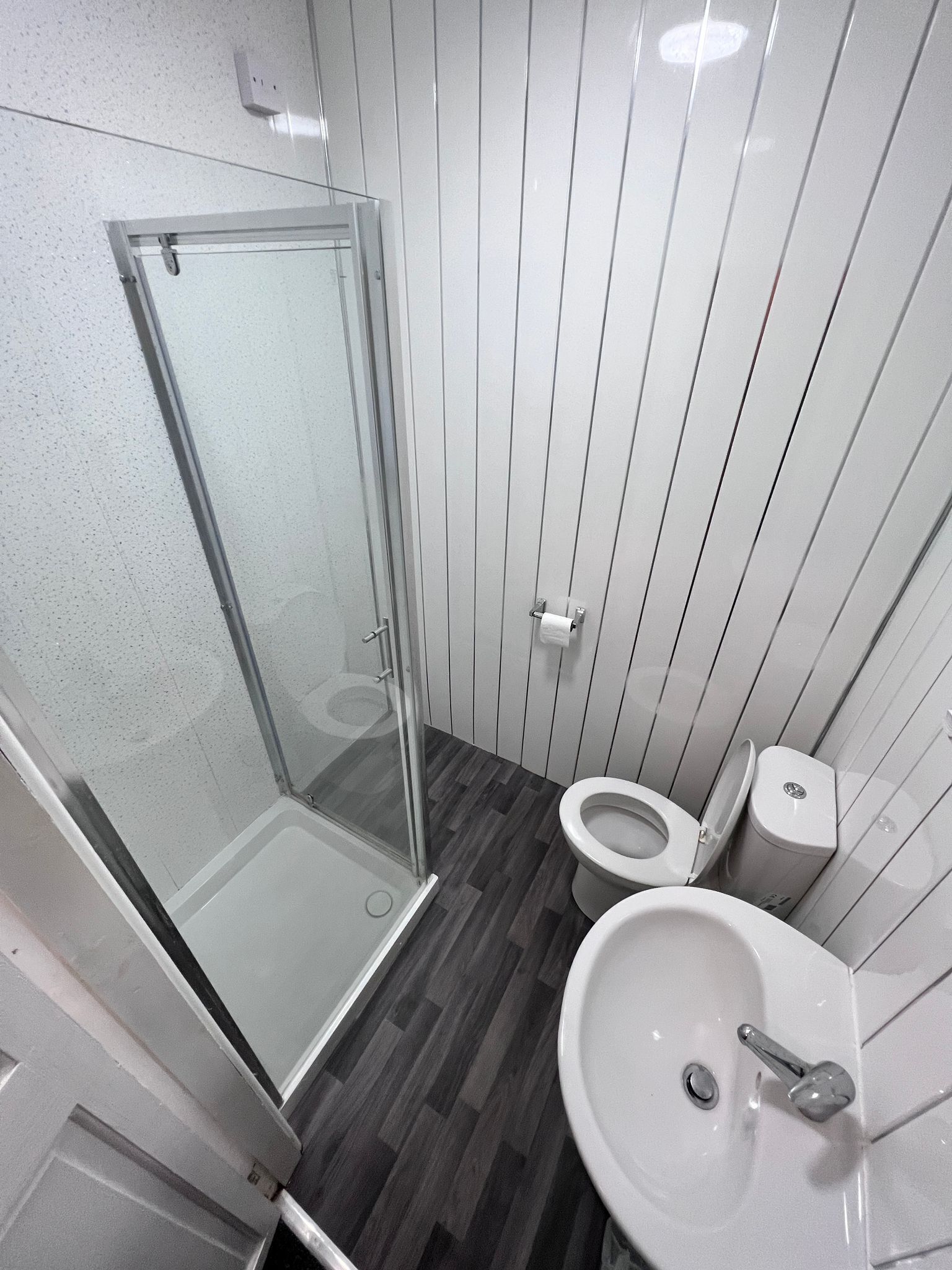 Een badkamer met een douchecabine van glas, toilet en wastafel.