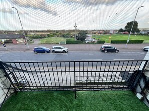 A parking area with multiple cars, a green lawn, and a fence. - Three Bedroom - Apartment ( Sea View ) (Skegness)