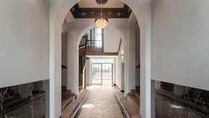 Um hall espaçoso com piso de mármore, teto em arco e lustre.