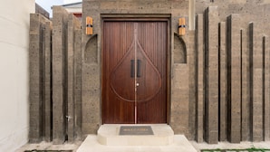 A large wooden door with a circular design, flanked by tall, narrow stone pillars. - Bellini Villa (Canggu)