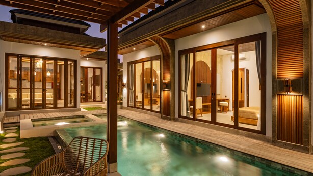 A modern resort with a swimming pool, wooden deck, and large glass doors leading to a well-lit interior. - Bellini Villa (Canggu)
