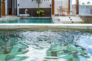 A swimming pool with clear water, a flamingo float, and a chair by the poolside. - Bellini Villa (Canggu)