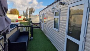 A row of mobile homes with a grassy patio area and a covered seating space. - Lovely pet Friendly 4 Berth Caravan in Morecambe (Morecambe)