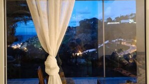 A room with a large window, a view of a landscape with trees and a road, and a checkered floor. - Charmante Villa vue mer (Tanger)