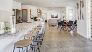 A modern kitchen with a marble countertop, bar stools, and a dining area with a table and chairs.