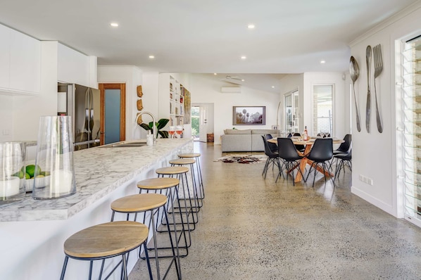 Una cocina moderna con encimera de mármol, taburetes de bar y comedor con mesa y sillas.