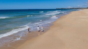 A beach with three people walking along the shore.