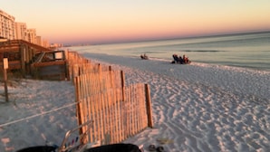 Una spiaggia con una recinzione in legno e alcune persone in lontananza.