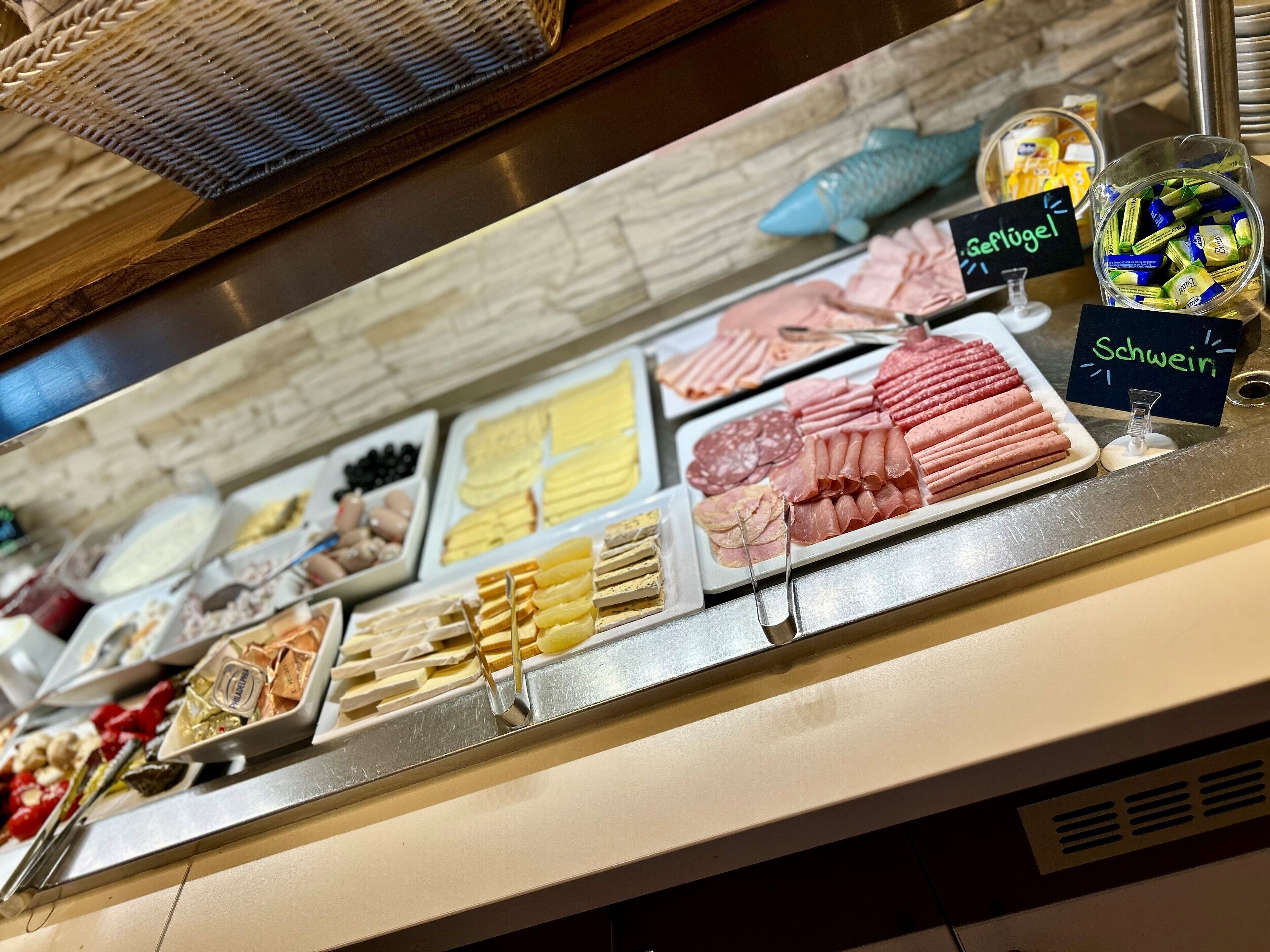 A buffet with various food items including meats, cheeses, and pastries.