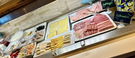 A buffet with various food items including meats, cheeses, and pastries.