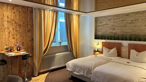 A hotel room with a wooden wall, a bed with white bedding, a desk with a chair, and a radiator. - Tauwerk Hotel (Wilhelmshaven)