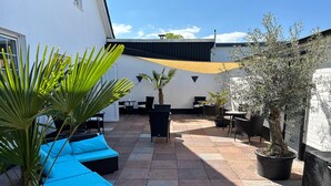 An outdoor patio with seating, potted plants, and a pergola. - Tauwerk Hotel (Wilhelmshaven)