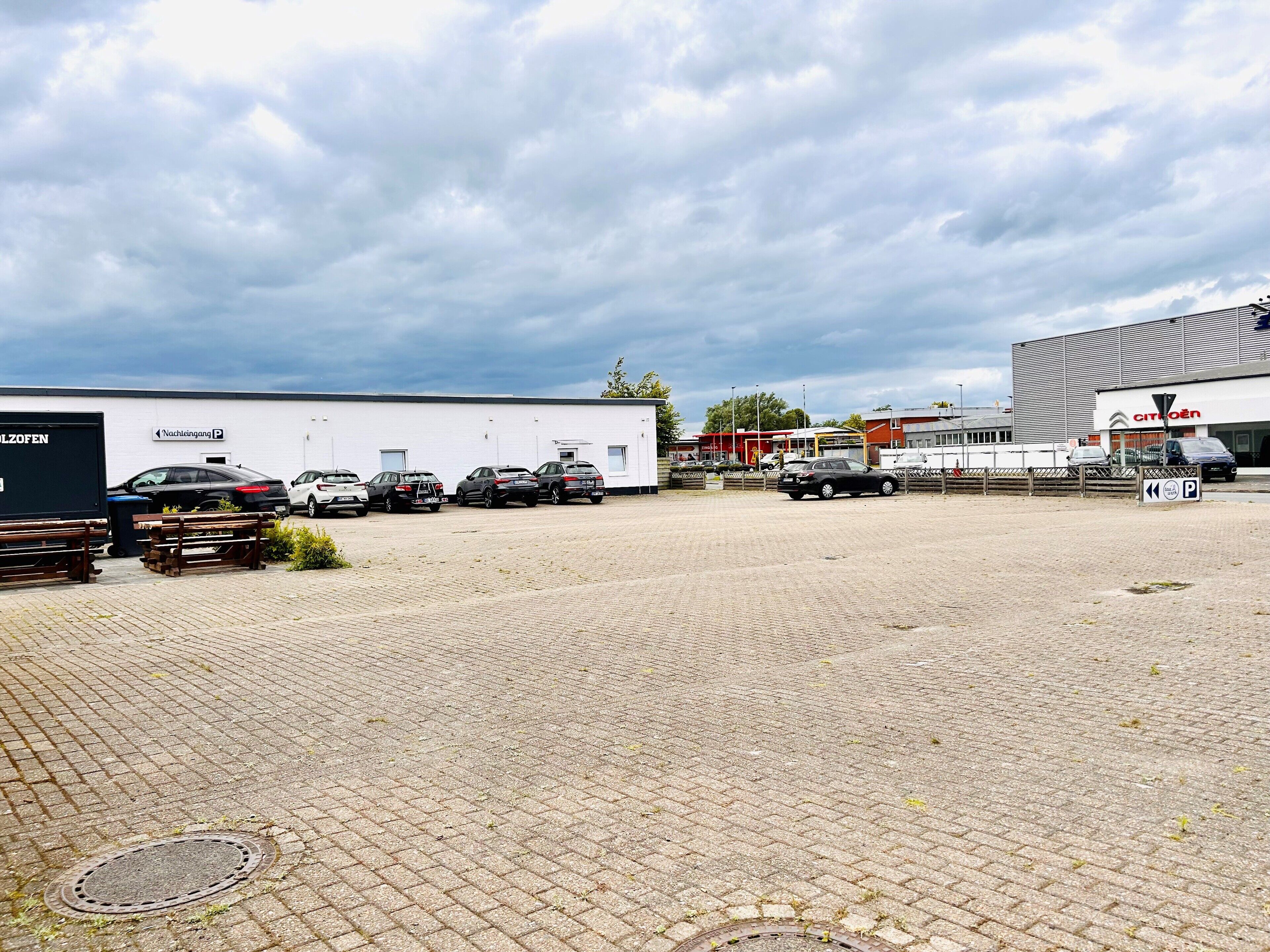 A parking lot with several cars and a large building in the background.