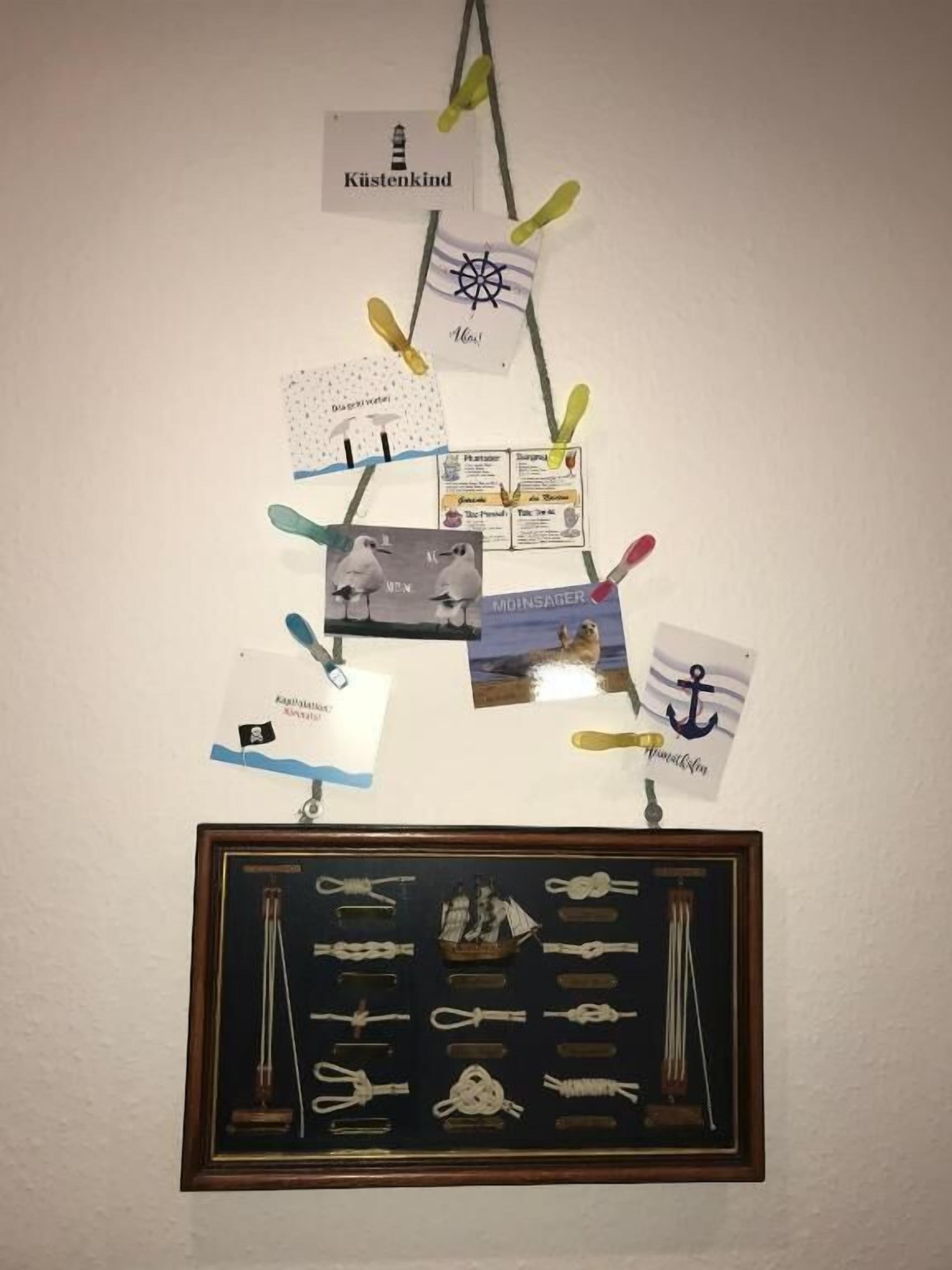 A wall with various nautical-themed decorations, including a framed collection of sailing equipment and several cards with maritime symbols.
