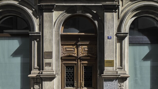 A building facade with a large, ornate wooden door, two arched windows on either side, and a plaque indicating the address. - URBANAUTS BELETAGES Sonata (Trieste)
