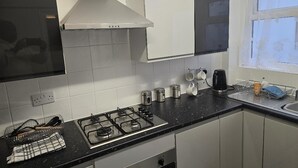 Une cuisine équipée d’une cuisinière à gaz, de meubles blancs, d’une hotte en acier inoxydable et d’une fenêtre offrant une vue agréable.