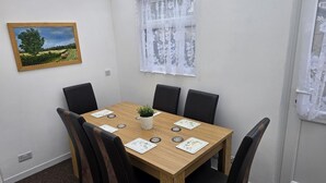 Un coin repas avec une table en bois, des chaises noires et une petite plante en pot.