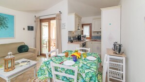 A compact living space with a dining area, kitchenette, and a sofa. - Villa del Golfo (Olbia)