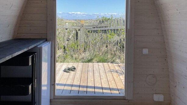 Interior de madera con vista a una terraza y valla de madera al exterior.