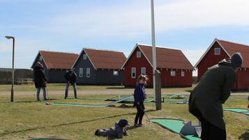 A group of people playing golf in an outdoor setting with houses in the background.