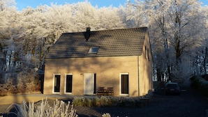 Une maison de plain-pied en briques, avec un toit en pente, une petite fenêtre et une cheminée.
