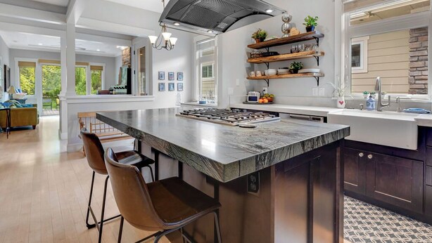 Una cocina moderna con una isla grande, taburetes de bar y estantes empotrados.