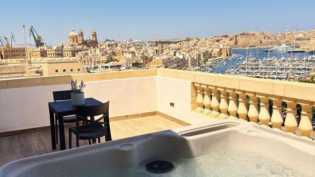 A rooftop terrace with a hot tub, a table, and chairs, overlooking a marina and cityscape. - Yolanda Boutique Hotel  (Birgu)