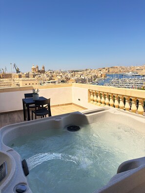 A rooftop terrace with a hot tub, a table, and chairs, overlooking a marina and cityscape. - Yolanda Boutique Hotel  (Birgu)
