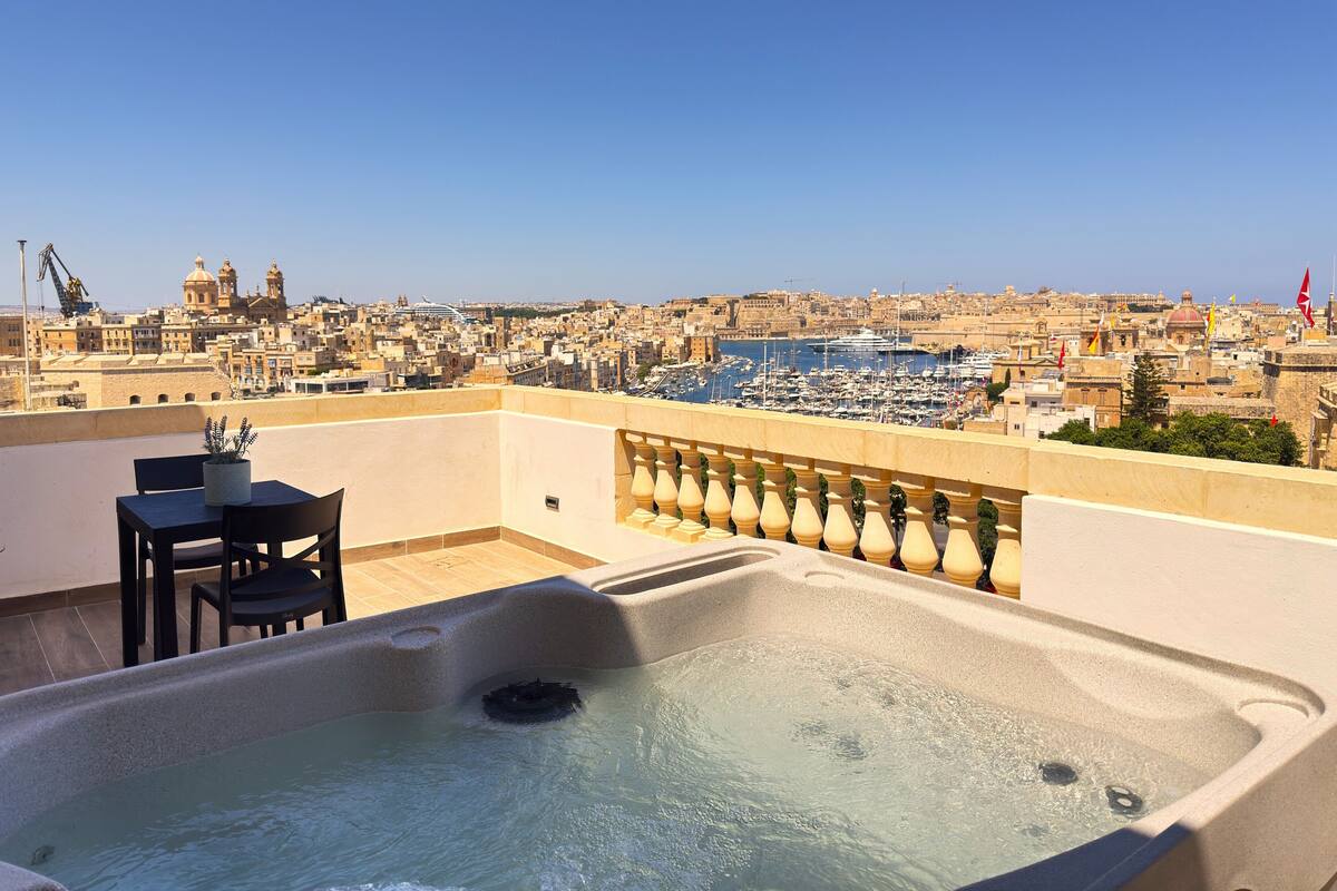 Terraza en la azotea con jacuzzi, una mesa y sillas.