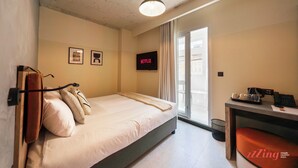 Una habitación de hotel con cama, escritorio, silla, televisor y ventana.