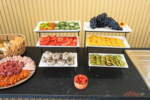 A buffet table with various food items including sliced vegetables, fruits, and meats. - Mosta Stays  (Mosta)