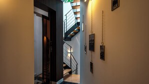 A modern interior with a staircase, a hallway, and a door leading to another room.
