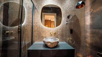 Un bagno moderno con lavabo in pietra, uno specchio grande e una zona doccia.