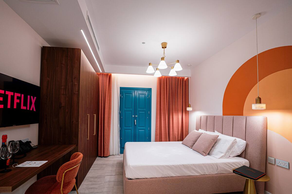 A hotel room with a bed, a desk with a TV, and a wardrobe.