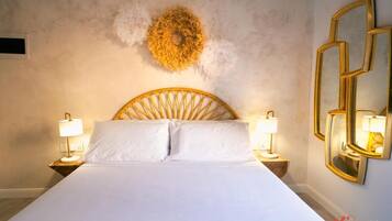 Un cuarto de hotel con una cama grande, dos lámparas de noche, un adorno en la pared y un espejo.
