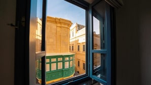 A view through a window of a building with a curved facade and a green awning.