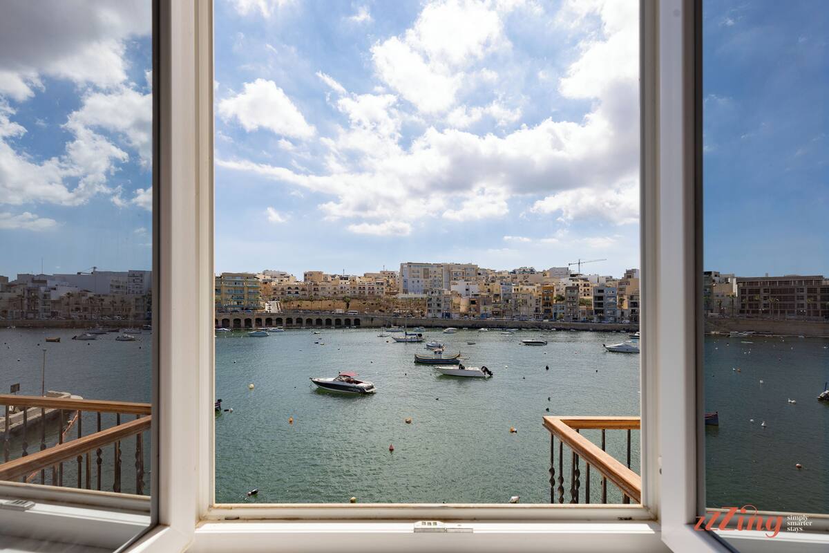 Vista dalla finestra su un porto con barche ed edifici.
