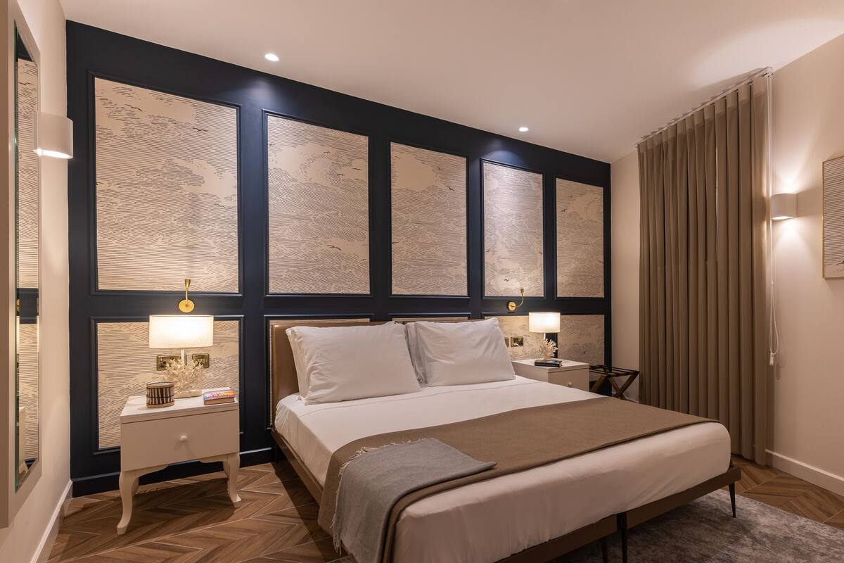 Una camera d'albergo ben ordinata con un letto grande, due comodini e una testiera decorata con pannelli.