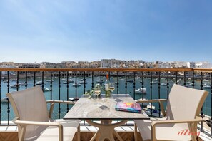Ein Balkon mit Tisch, zwei Stühlen, einer Weinflasche und einem Buch.