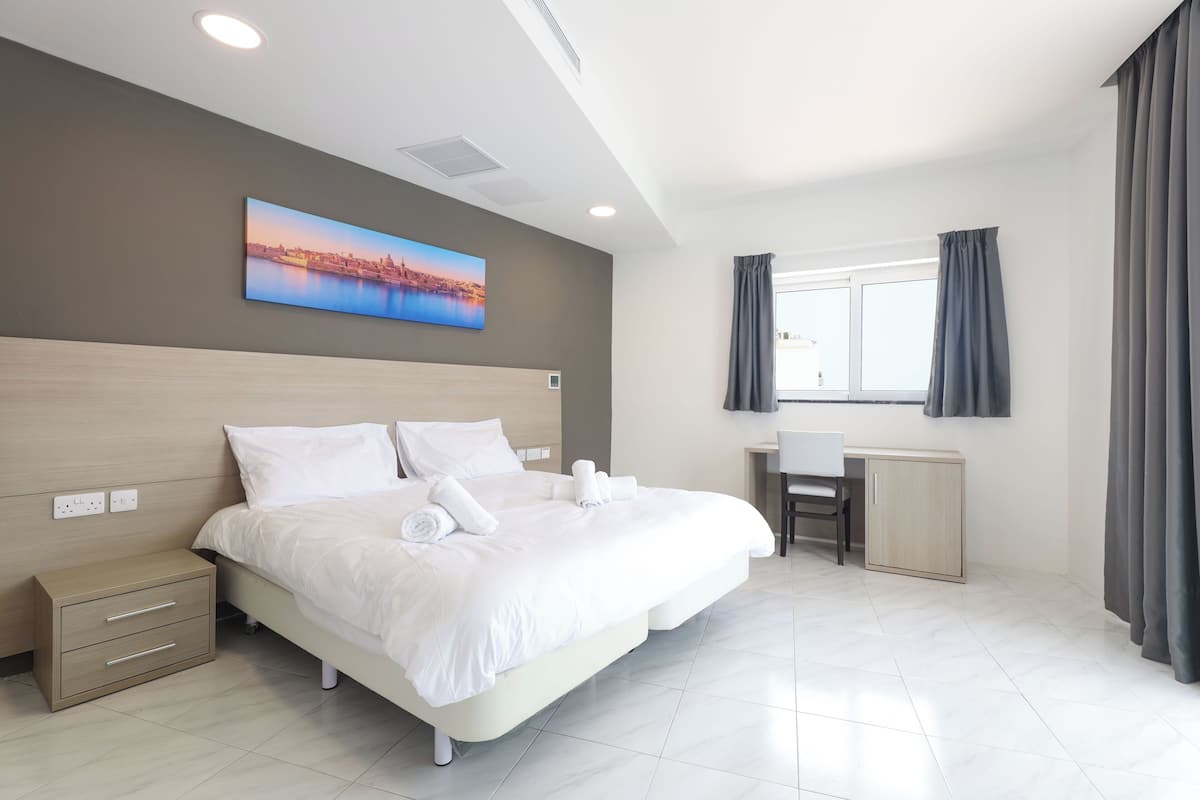 Ein modernes Hotelzimmer mit einem großen Bett, einem Schreibtisch und Blick auf die Stadtlandschaft.