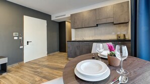 Una cocina moderna con armarios oscuros, una encimera blanca y un comedor con una mesa redonda preparada para dos personas.