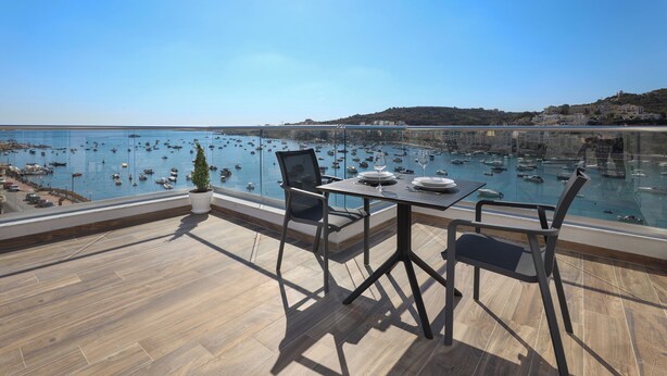Terraza con mesa y sillas que da a un puerto deportivo con barcos.
